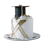 Graduation-themed cake with a cap, diploma, and tassel on a white background