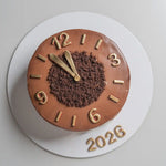 Chocolate cake designed like a clock with gold numbers and '2026' on a white background