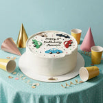 A round white-frosted birthday cake with car decorations and the text 'Happy 5th Birthday Maxwan' sits on a table covered with a light blue polka-dot cloth. Gold, pink, and yellow party hats, cups, and confetti are arranged around it against a light blue background.