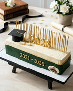 Graduation-themed cake with '2021-2026' and a graduation cap on a stand.