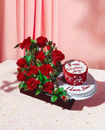Bouquet of red roses and a red cake with white frosting on a light pink background