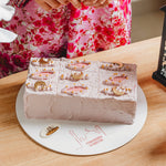 Decorative cake with intricate designs on a white plate, placed on a wooden table.