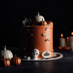 Halloween-themed cake with pumpkins and skulls on a dark background