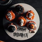 Halloween-themed cupcakes on a white plate with 'Happy Halloween' text.