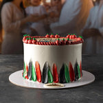 Decorative cake with red, green, and black icing on a dark surface