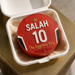 Red container with 'SALAH 10 The Egyptian King' text on a beige surface