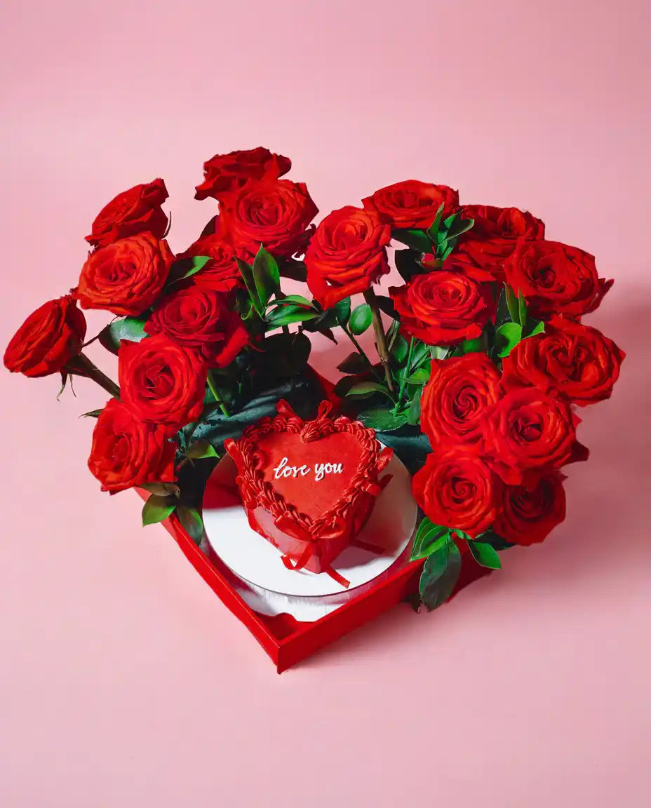 Heart-shaped box with red roses and a heart-shaped 'love' card on a pink background
