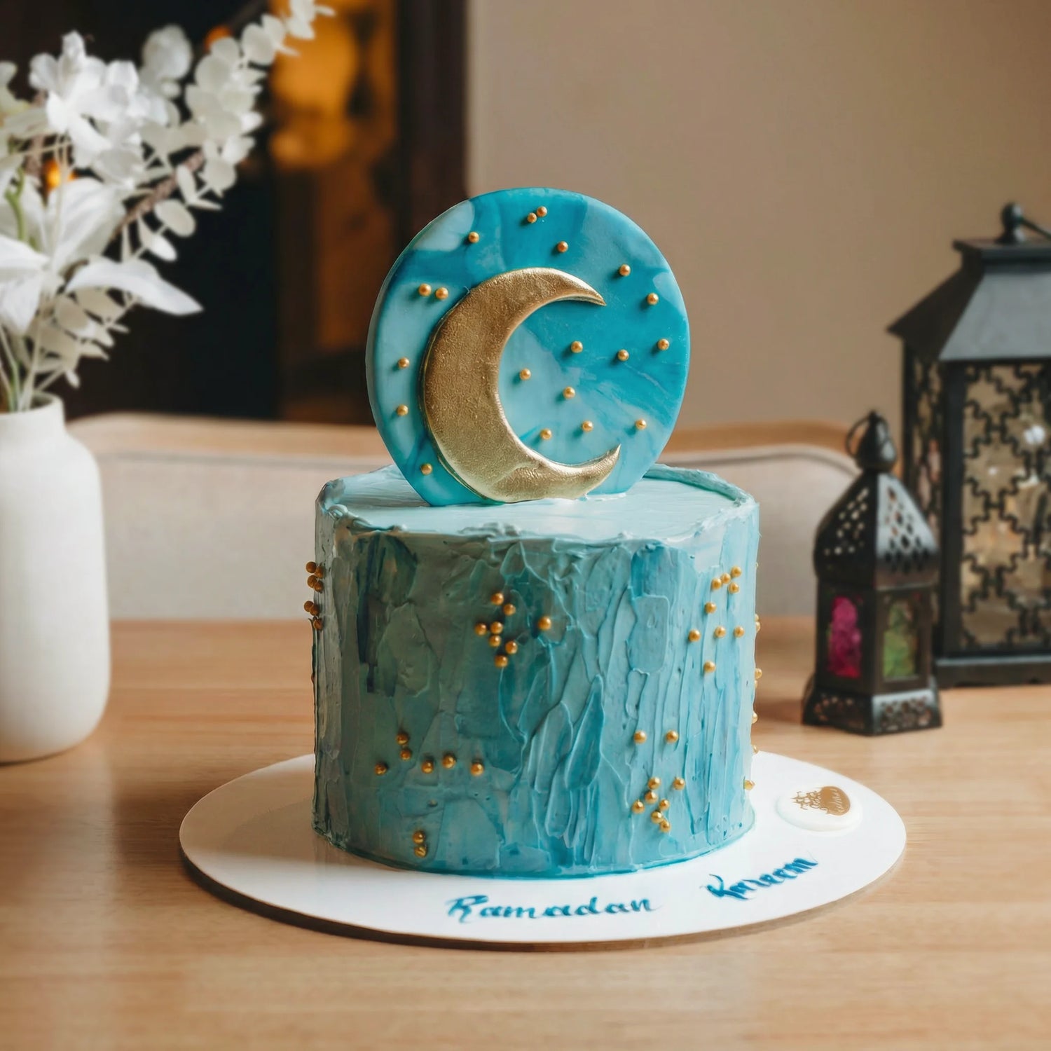 Blue cake with moon decoration on a wooden table, featuring 'Ramadan Kareem' text.