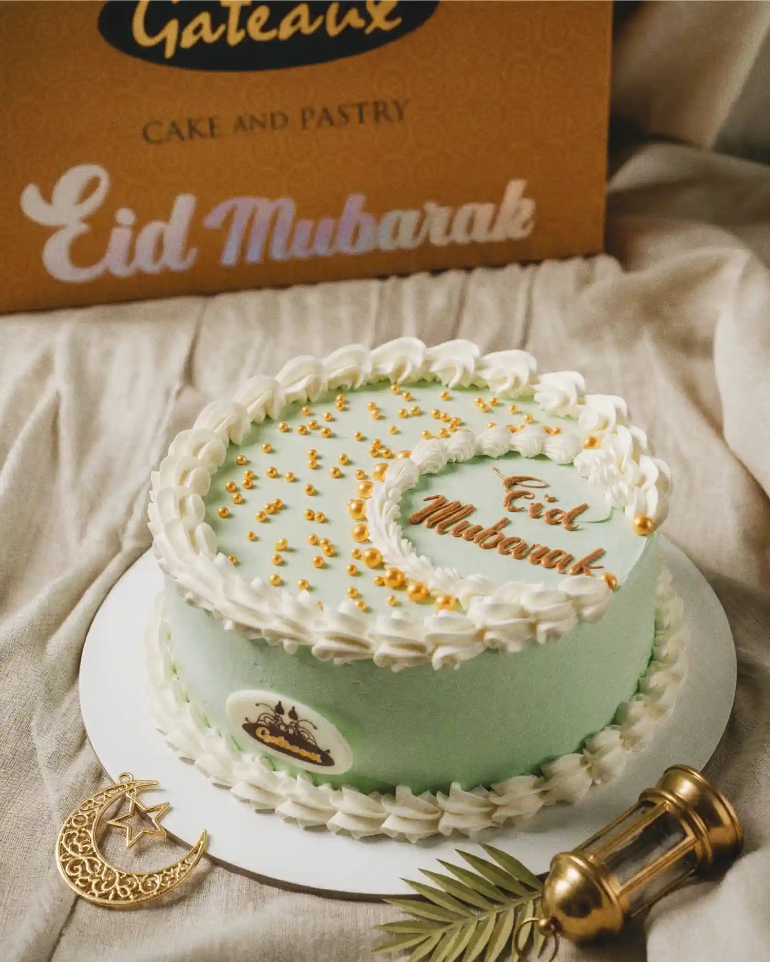 Decorative cake with 'Eid Mubarak' text, Gateaux Cake and Pastry box in the background