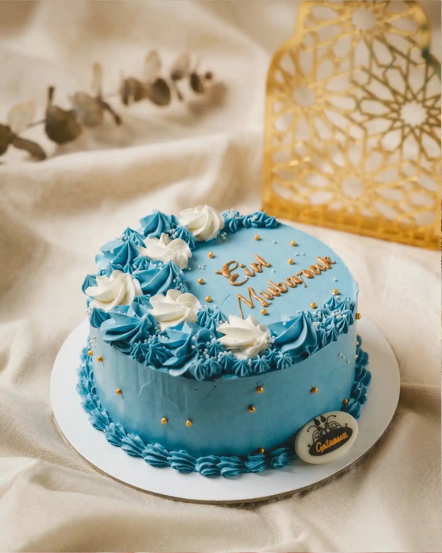 Blue cake with white flowers and 'Best Mommy' text on a beige background