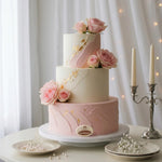 Three-tiered wedding cake with pink and white frosting, decorated with pink roses, on a white table with a soft focus background.