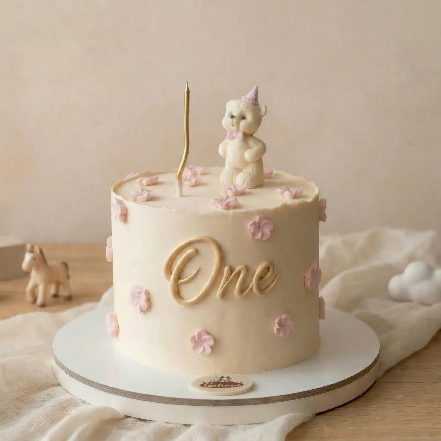 Children's birthday cake with a unicorn topper and 'One' candle on a neutral background