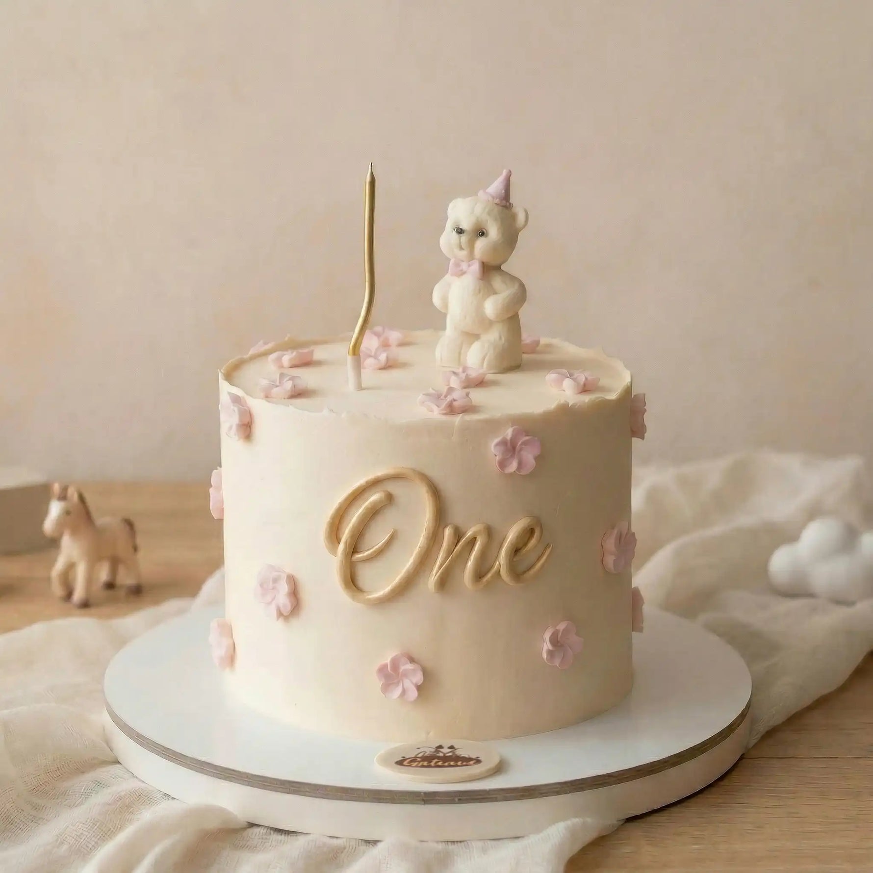 Children's birthday cake with a unicorn topper and 'One' candle on a neutral background