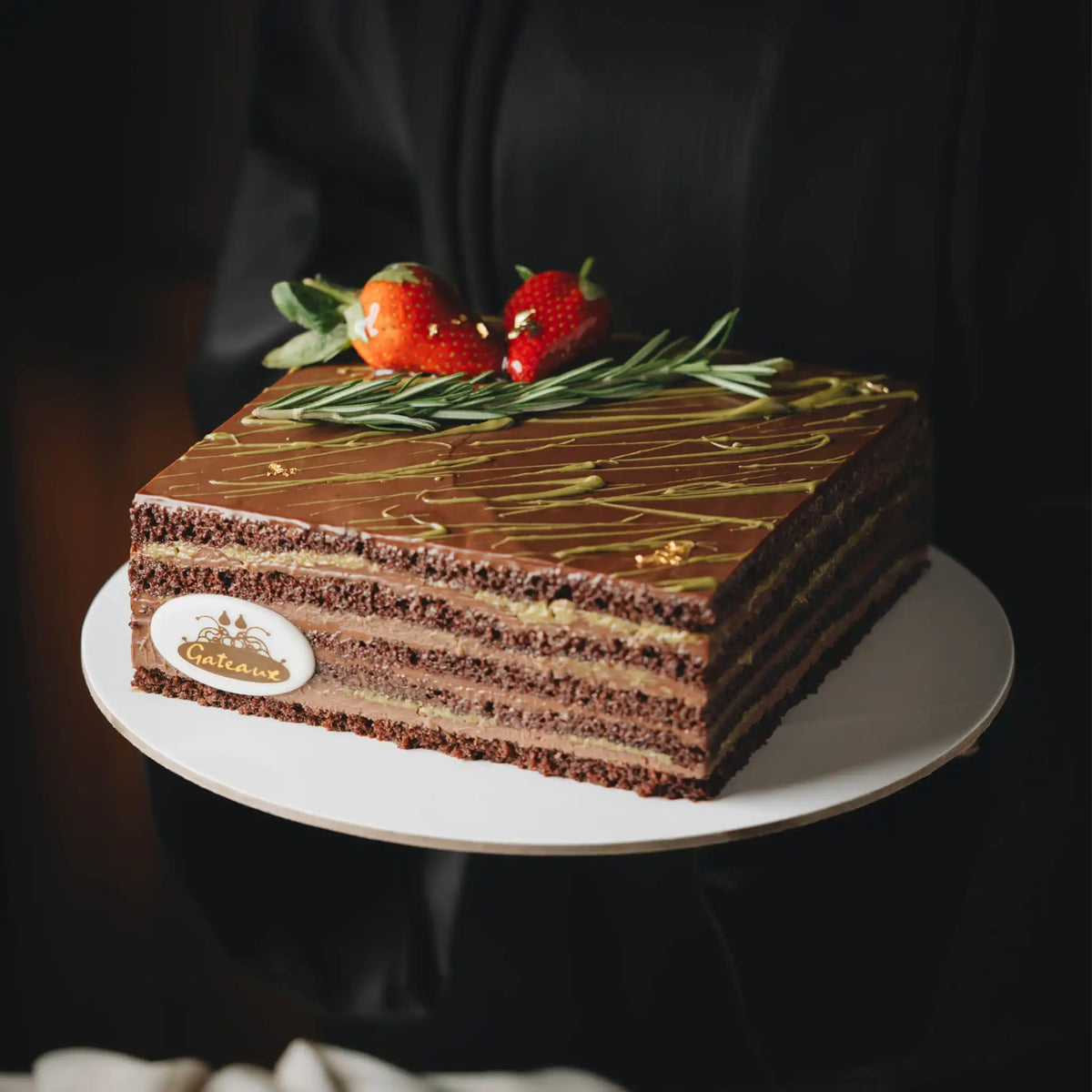 Chocolate cake with strawberries on a white plate against a dark background