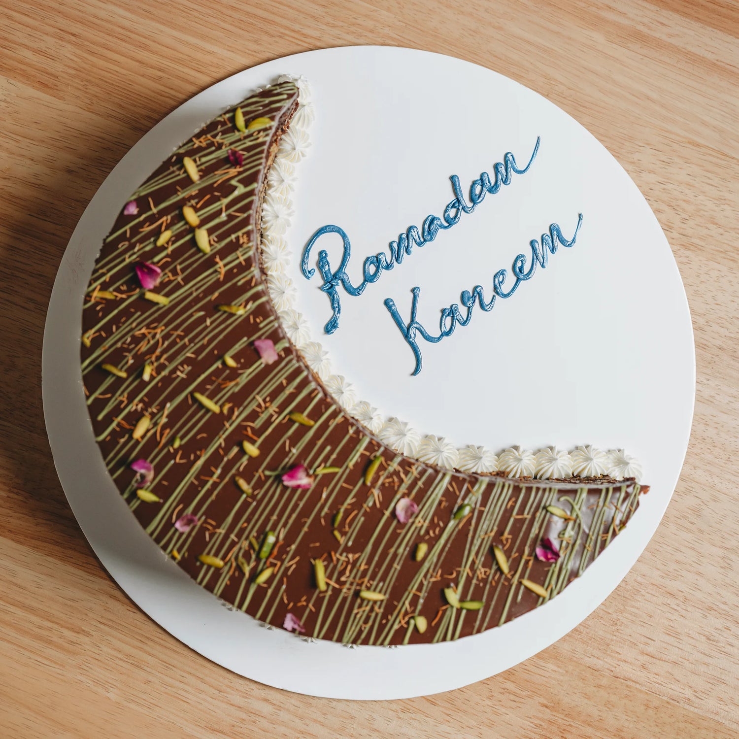 Chocolate crescent moon cake with 'Ramadan Kareem' text on a wooden surface