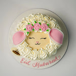 Decorative cake with a face, flowers, and 'Eid Mubarak' text on a white background