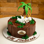 Chocolate cake with elephant and palm tree decorations on a white plate.