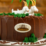 Chocolate cake with decorative elements resembling a landscape and 'Gateaux' branding.