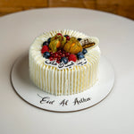 Decorative cake with fruits and 'Eid Al Adha' text on a white plate.