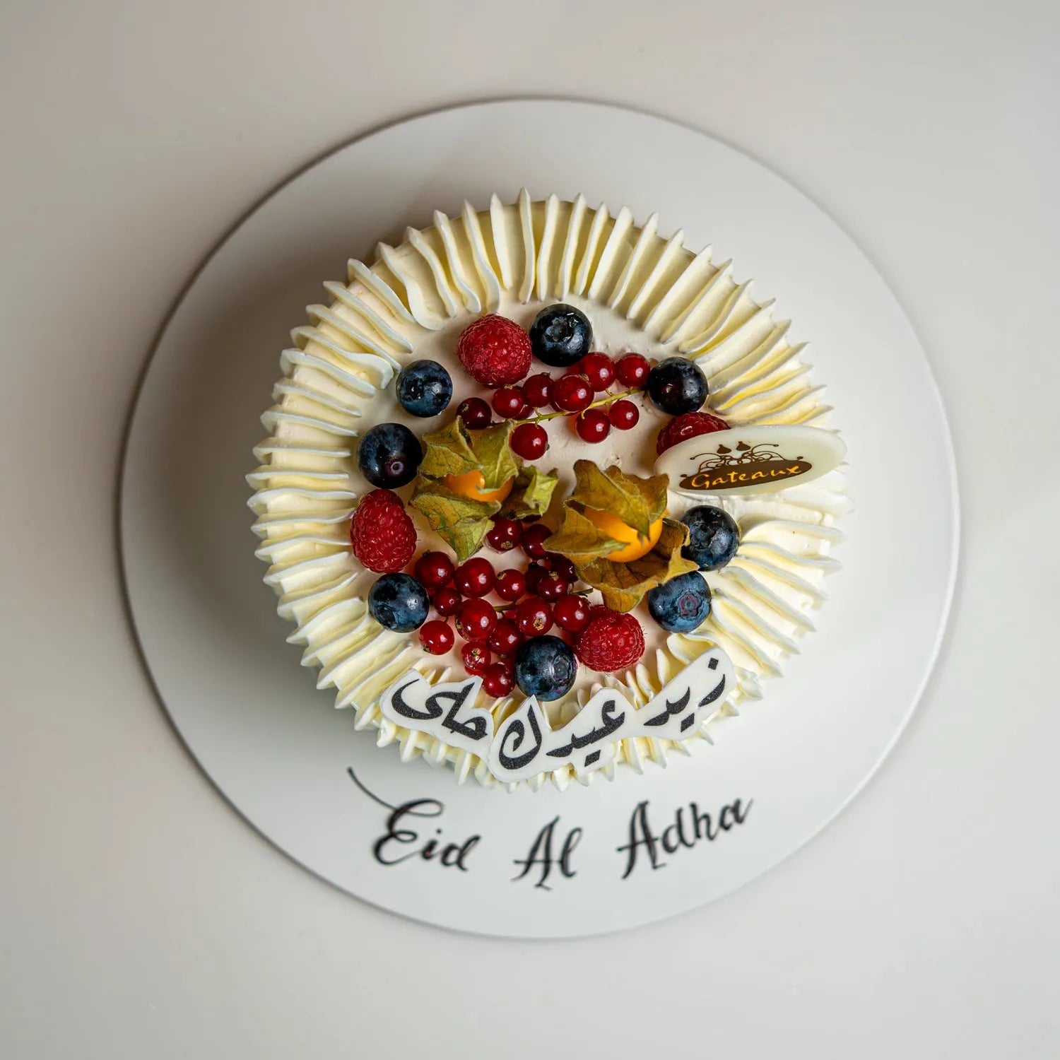 Decorative cake with fruits on a white plate with 'Eid Al Adha' text