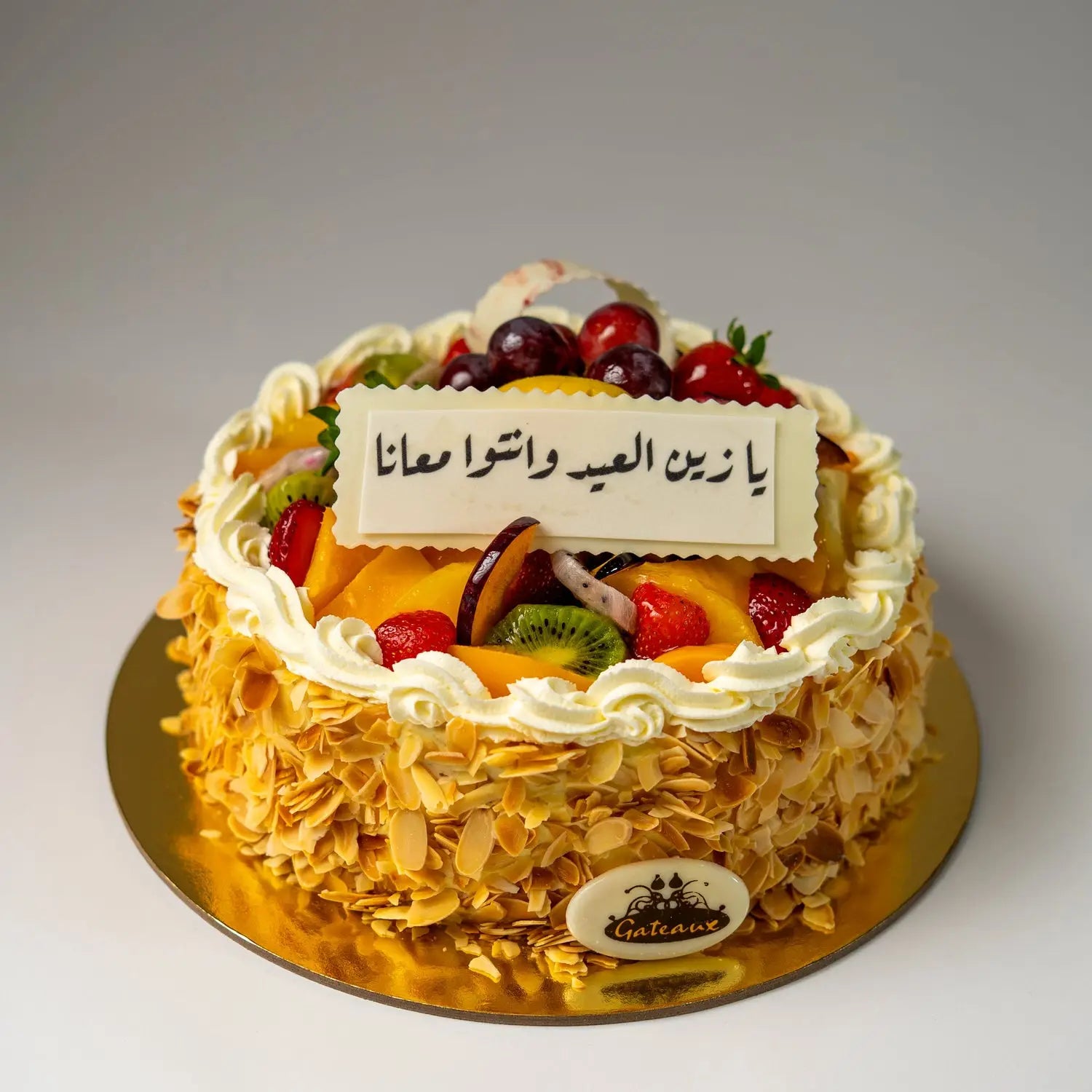Decorative cake with fruit toppings and a nameplate on a white background