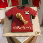 Red sports jersey cake with a gold trophy on a white plate