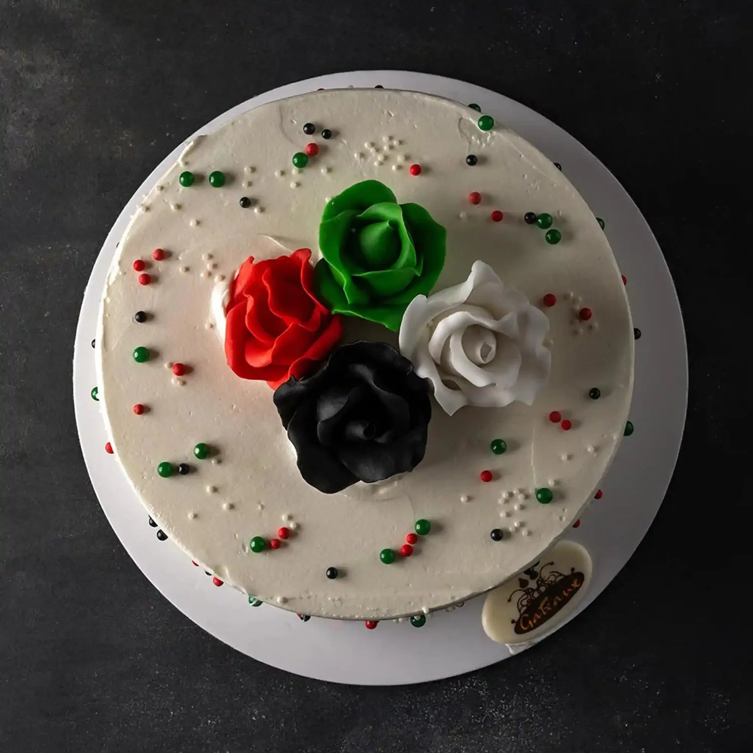 Decorative cake with red, green, and black roses on a dark background