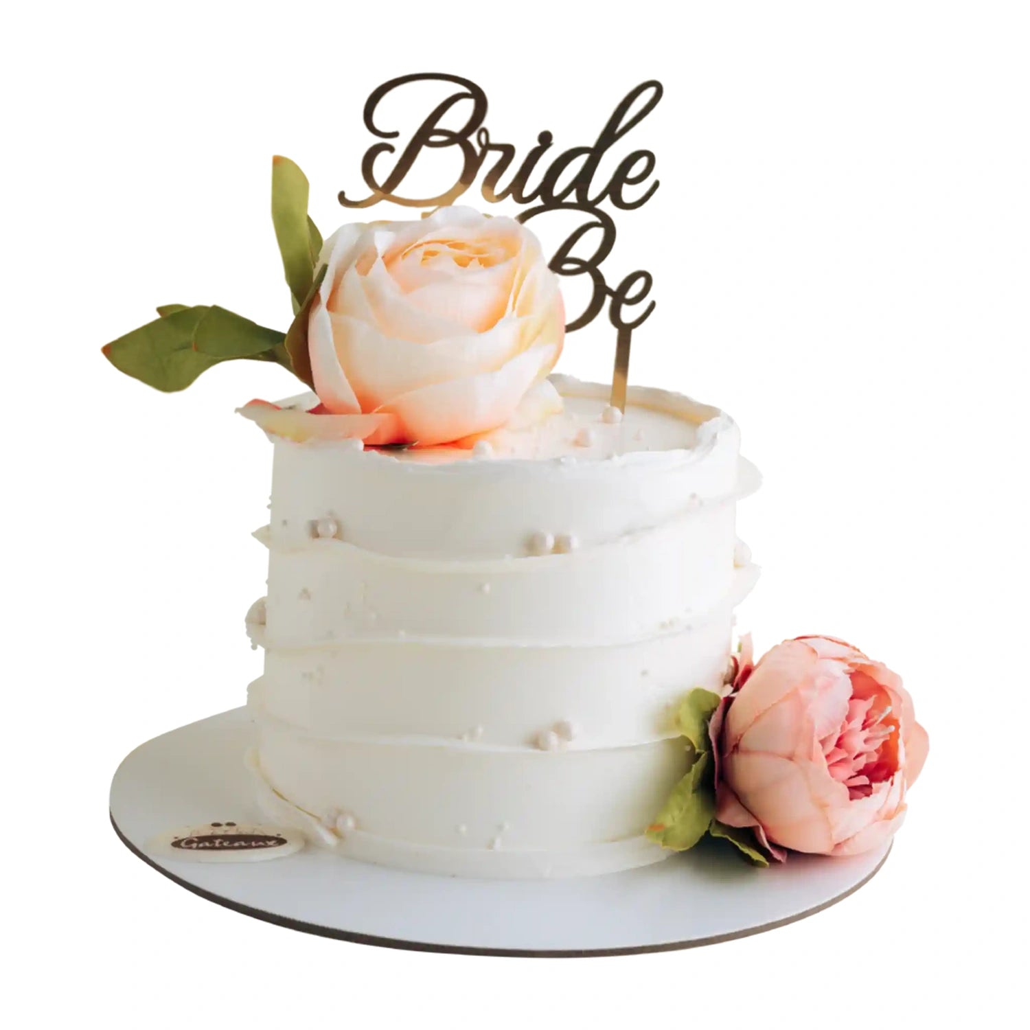 White cake with pink roses and 'Bride Be' topper on a white background