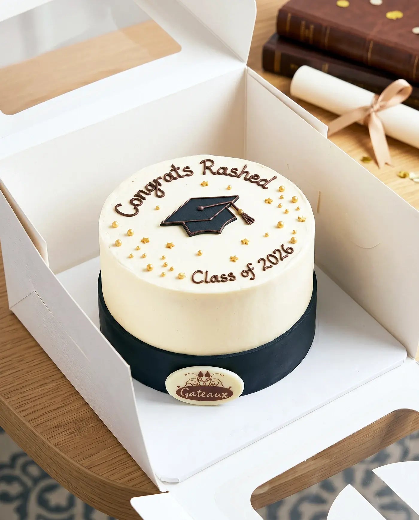 Graduation-themed cake with 'Congrats Rashed Class of 2016' text, displayed in a box.