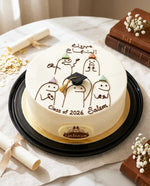 Graduation-themed cake with cartoon penguins and text on a white surface.