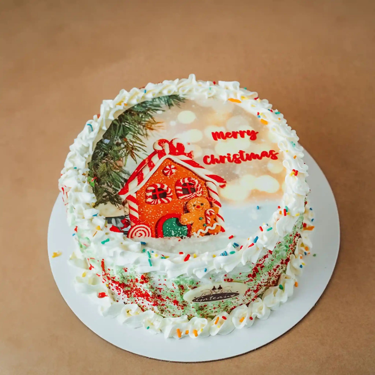 Christmas-themed cake with gingerbread house and 'Merry Christmas' text on a brown background