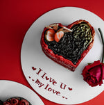 A heart-shaped cake with red and black icing, decorated with a message that reads 'I love u my love.