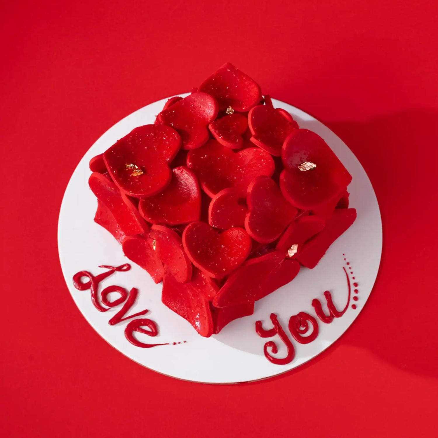 Red heart-shaped cake with 'Love You' text on a red background