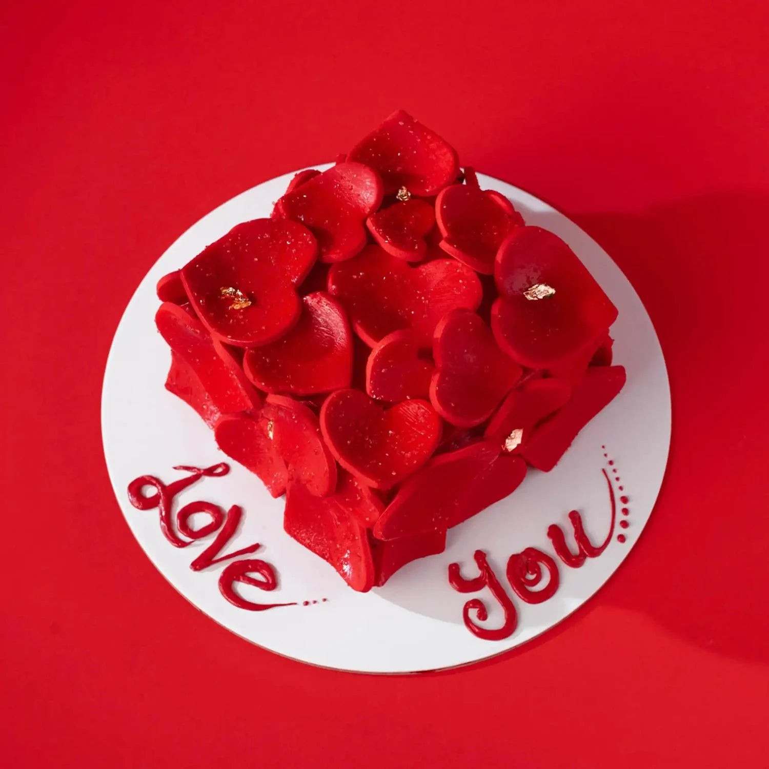 Heart-shaped cake with red roses on a red background with 'Love You' text