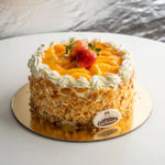 Decorative cake with fruit on a white plate, featuring the 'Gateau' brand.
