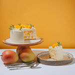 White cake with fruit on a wooden stand against an orange background