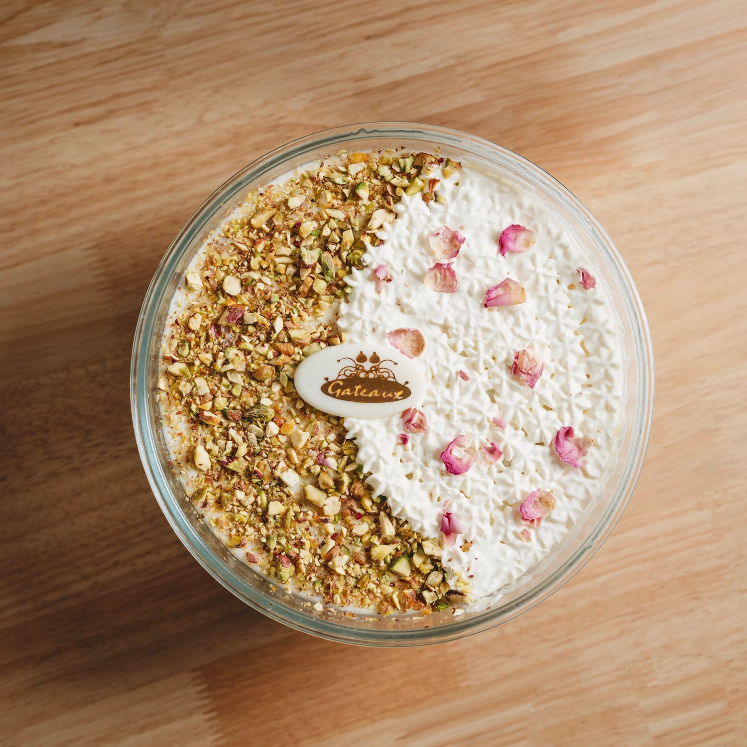 Dessert in a glass bowl with nuts and whipped cream on a wooden surface