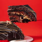 Chocolate cake with a slice being lifted against a red background