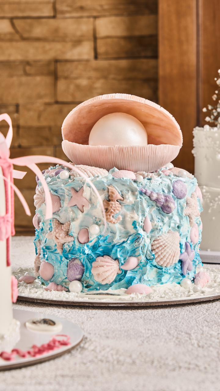 Decorative cake with seashells and a pearl on a wooden surface
