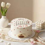 A round white frosted cake on a white plate, decorated with a printed calendar for March, small red heart details, and the words 'March' and 'Day of love'. A small oval plaque at the front reads 'Galantine'.