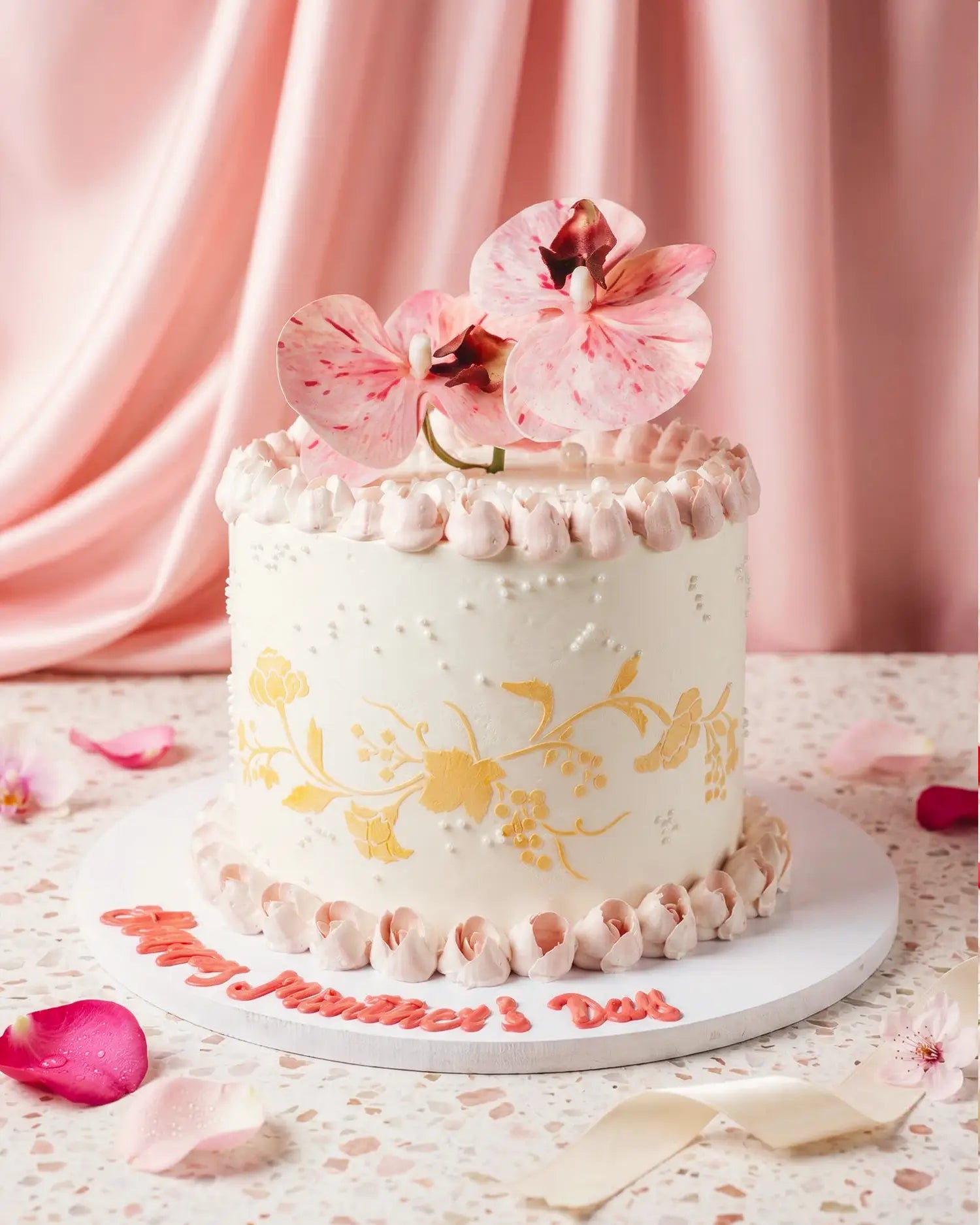 Decorative cake with pink flowers and gold accents on a pink background