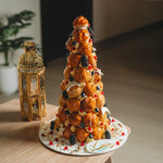 Decorative croquembouche tower on a plate with a lantern in the background
