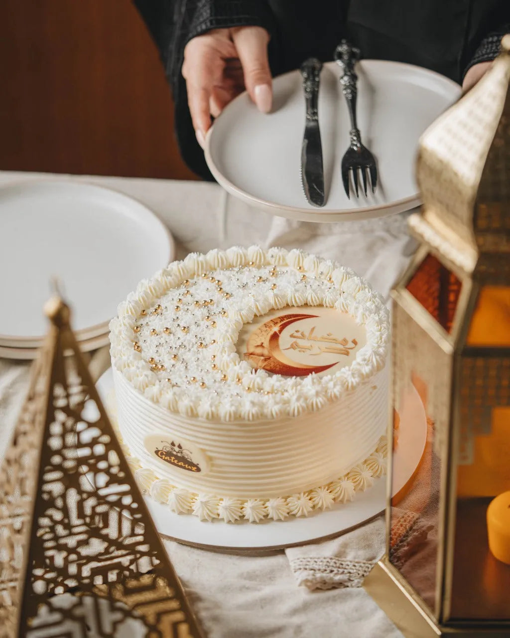 White cake with decorative elements on a table setting with plates and cutlery.