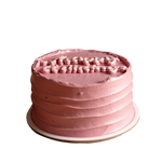 A small, round, pink birthday cake with decorative frosting and sprinkles on top.