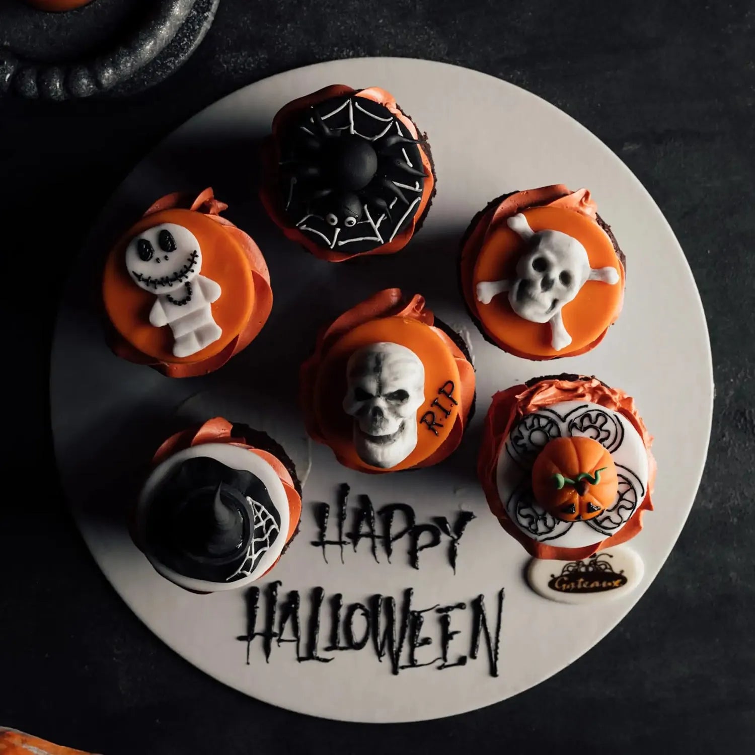 Halloween-themed cupcakes on a white plate with 'Happy Halloween' text.