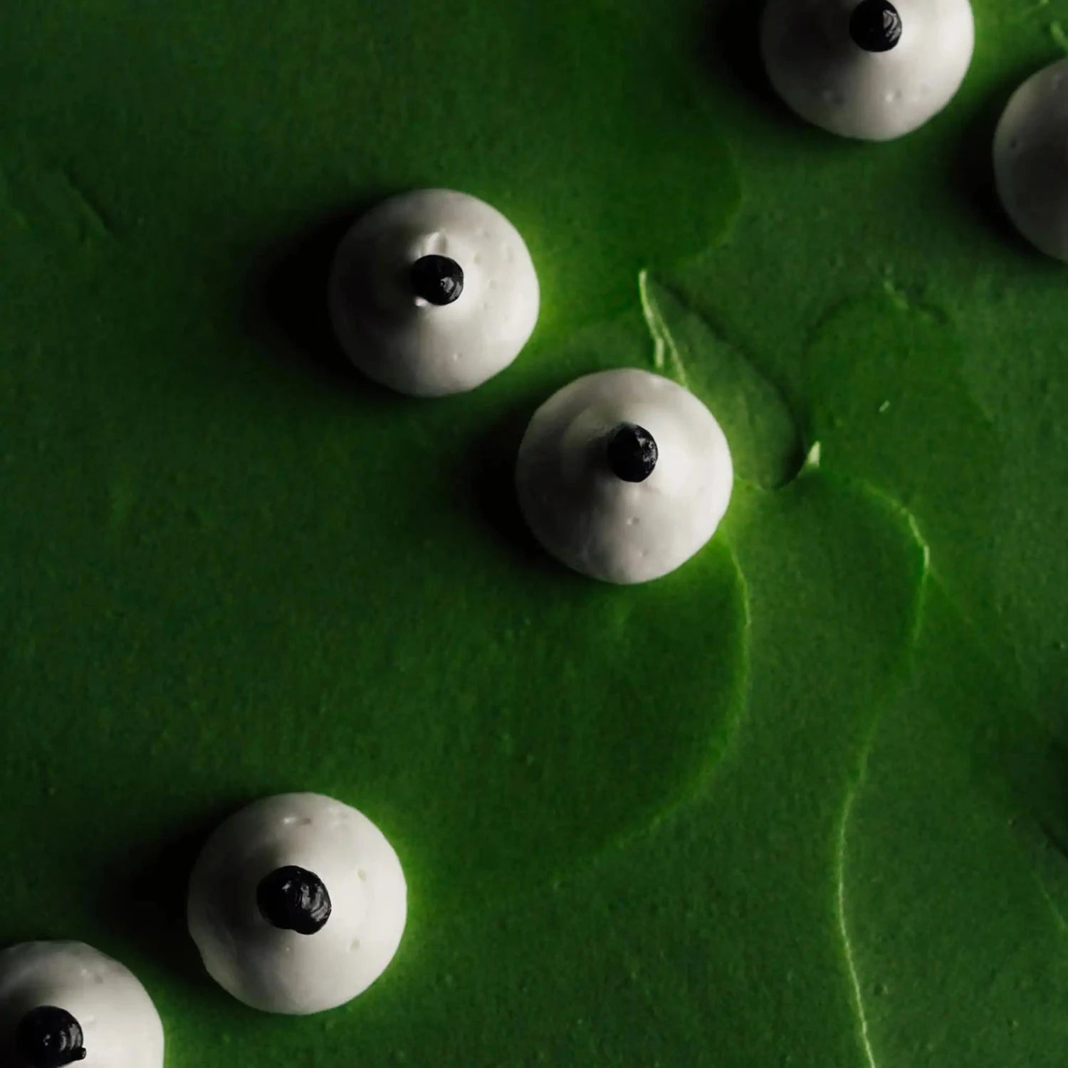 White spherical objects with black centers on a green textured surface