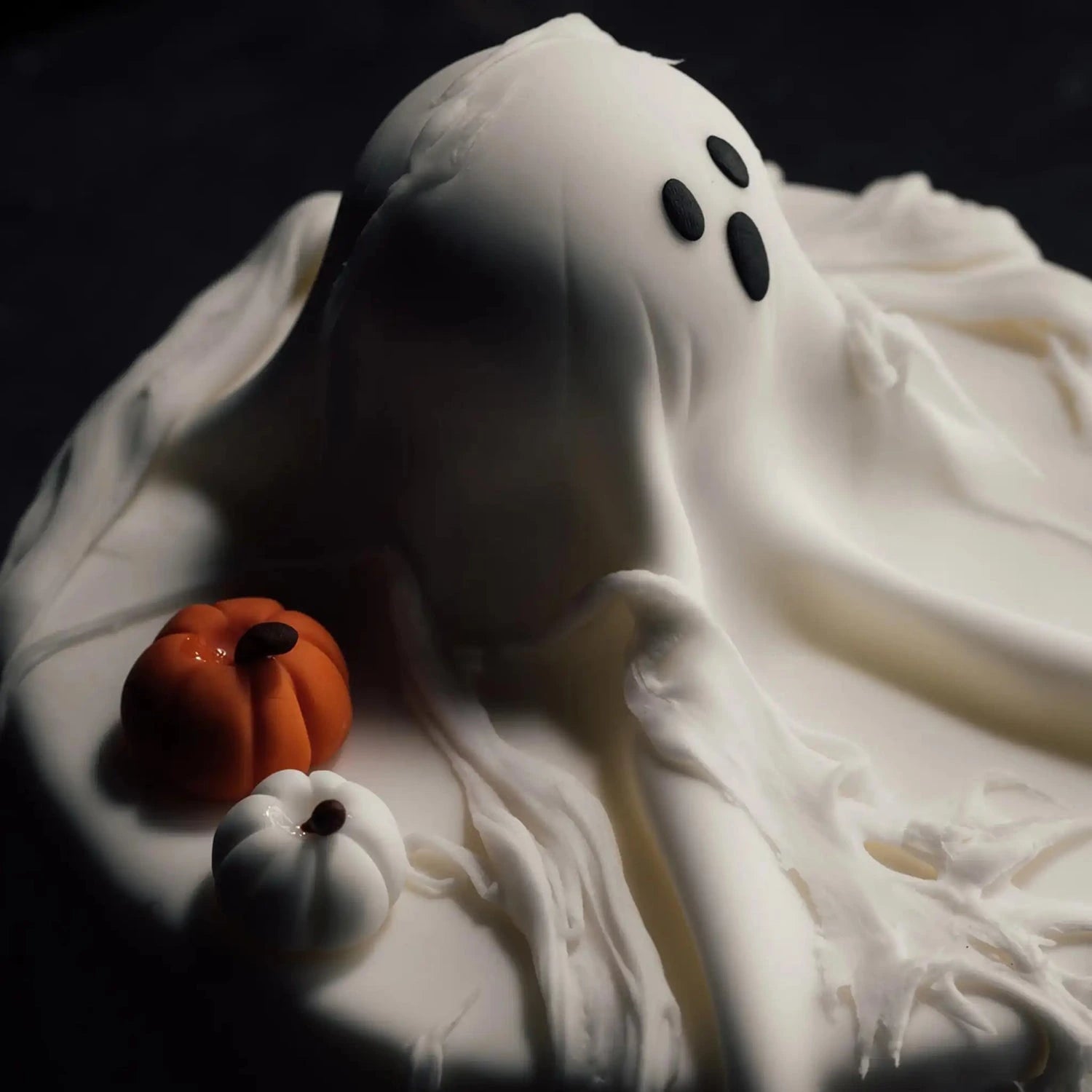 Ghost cake with pumpkins on a dark background