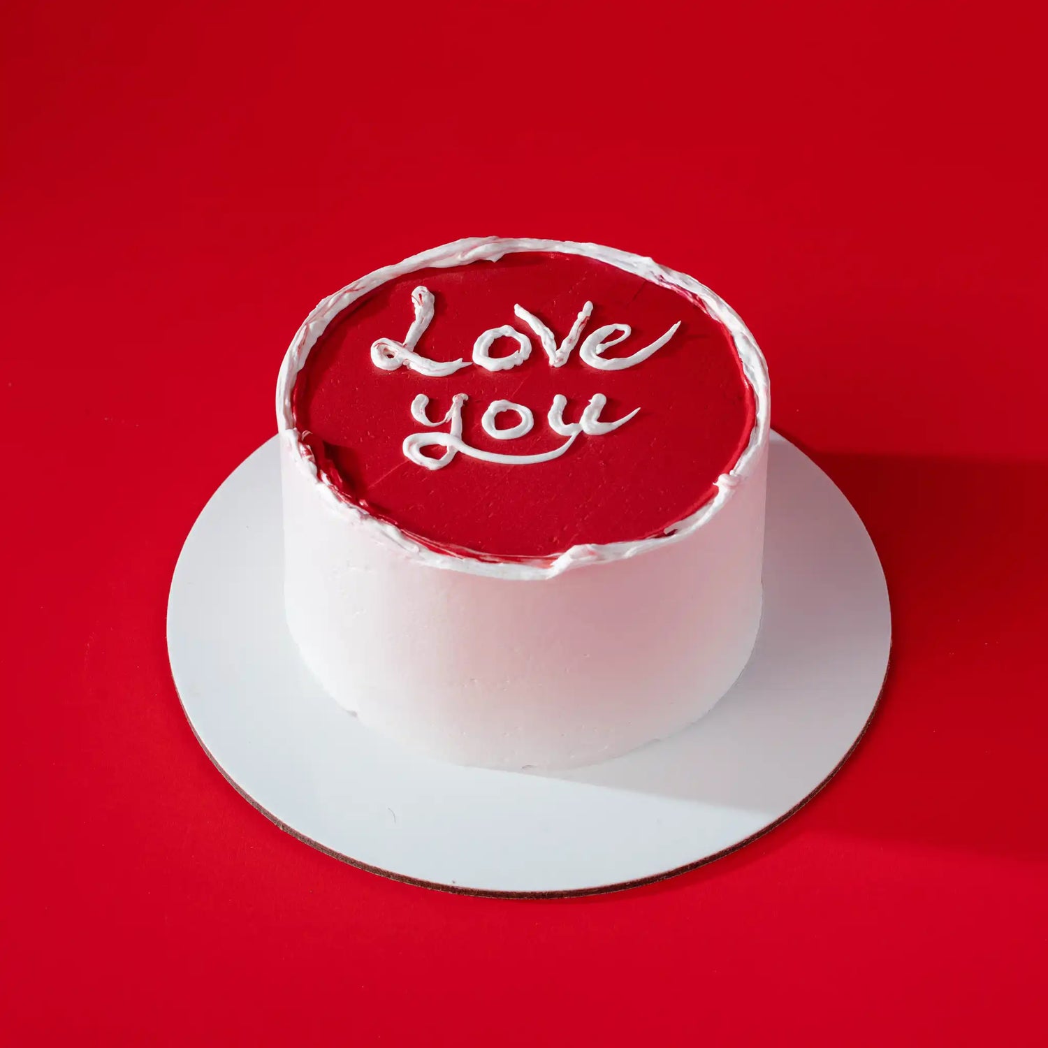 Small round cake with 'Love you' text on a red background