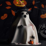 Halloween-themed ghost cake with spiders and pumpkins on a dark background
