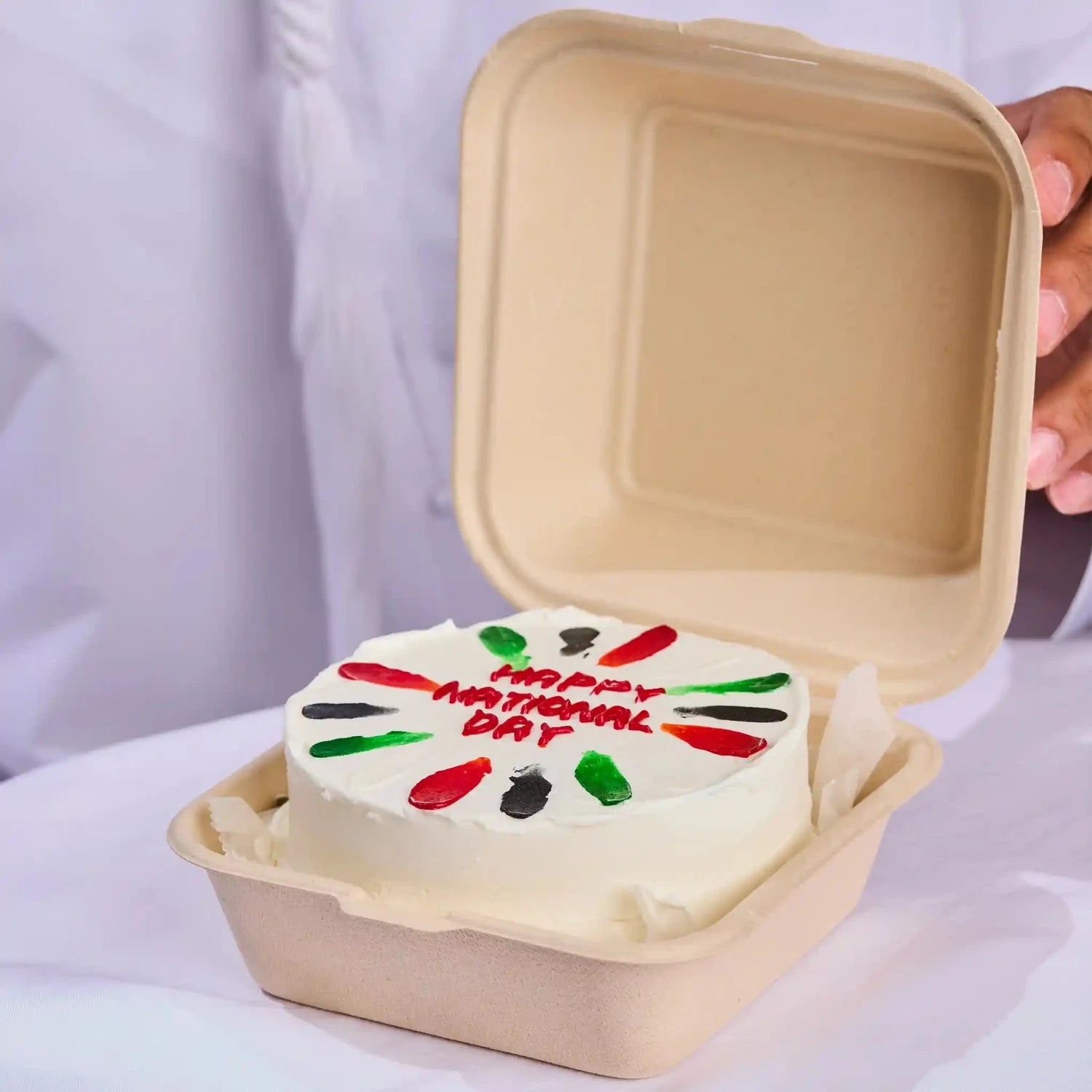 Small cake with 'Happy National Day' text in a cardboard container